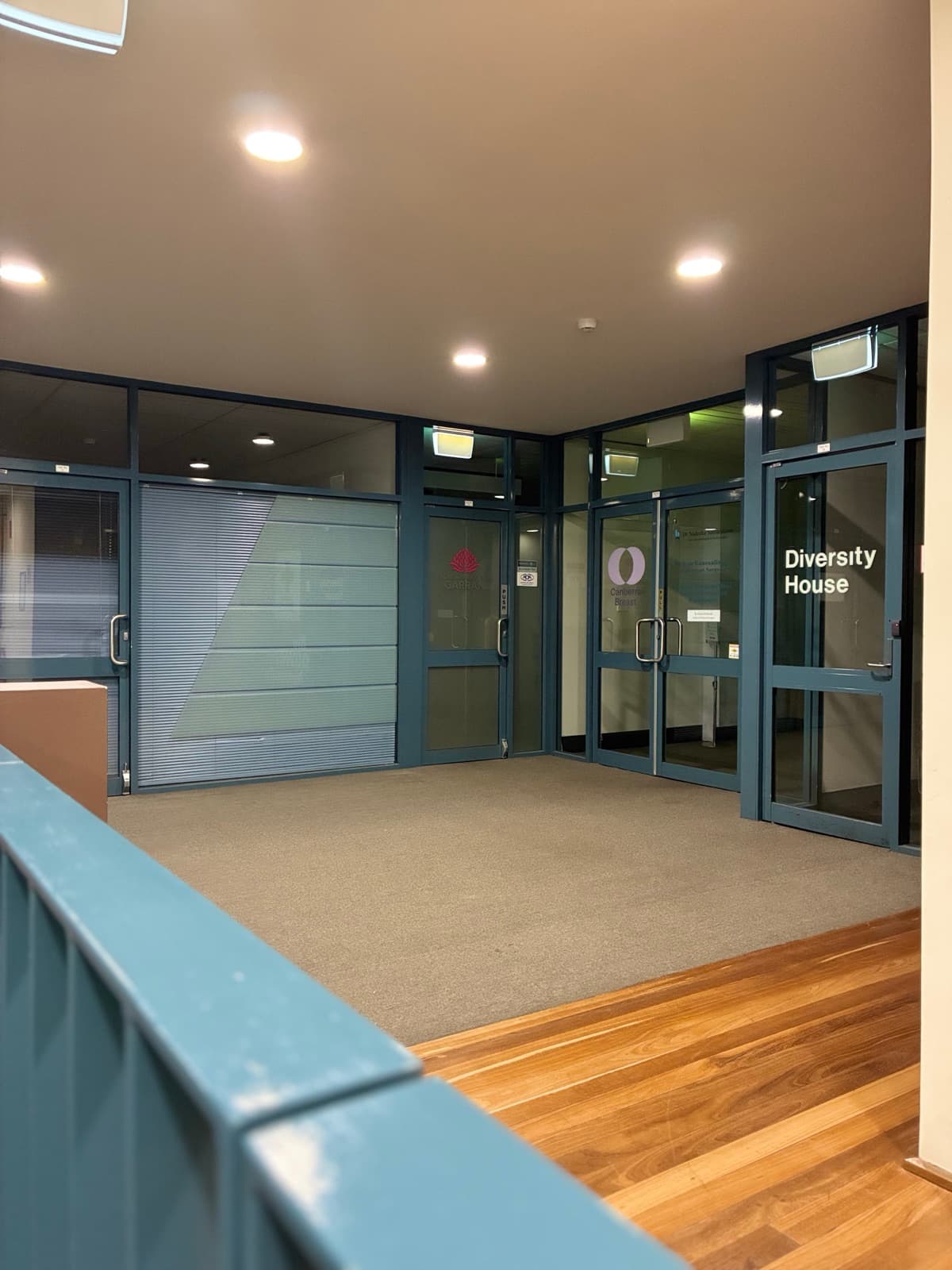 First-floor entrance with glass doors marked with the Canberra Breast logo, beside Diversity House.
